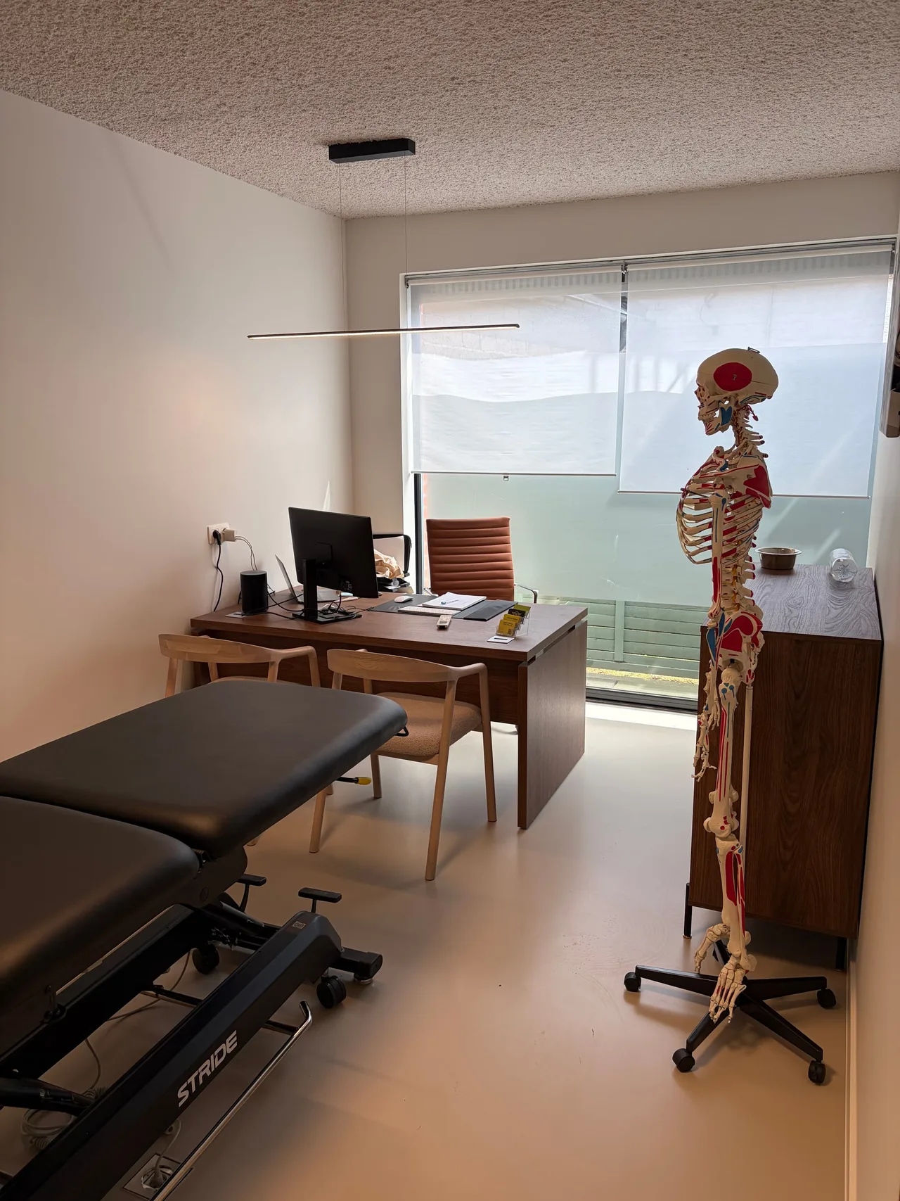 Bureau met computer, behandeltafel en een anatomisch skelet
